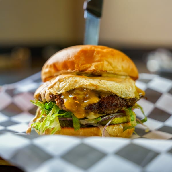 A Lindy's on 4th burger with a fried egg, melted cheese, lettuce, and pickles.