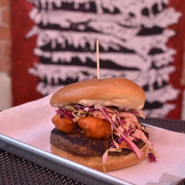 Lindy's on 4th burger with a thick patty, fried cheese curds, and coleslaw on a bun.