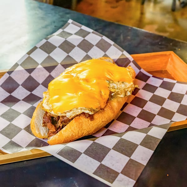 A Lindy's on 4th burger with melted cheese and a fried egg on a checkered paper-lined tray.