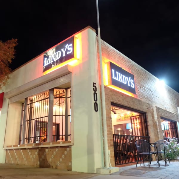 Exterior of Lindy's on 4th at night, with glowing signs and visible interior through windows.