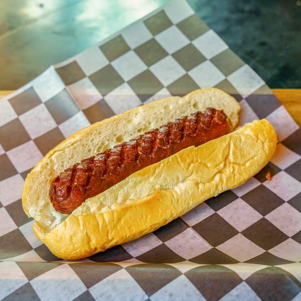 A grilled hot dog in a bun, served on checkered paper at Lindy's on 4th.