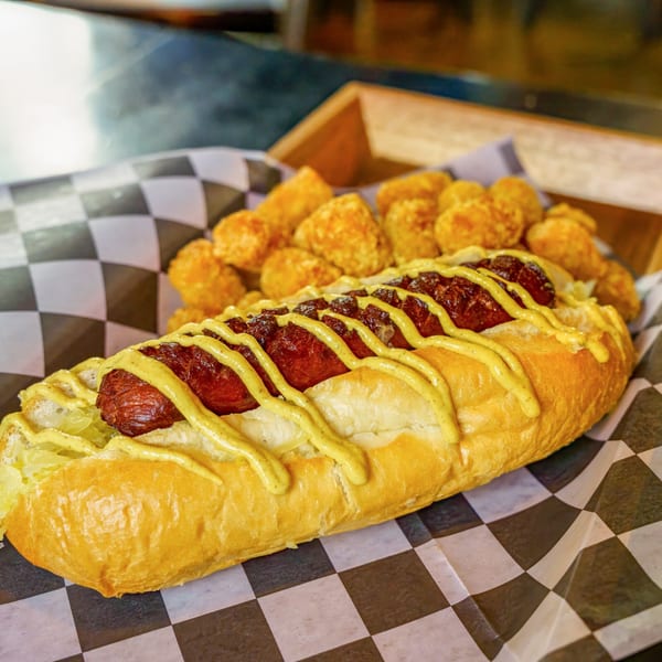 Lindy's on 4th hot dog with mustard and relish, served with a side of tater tots.