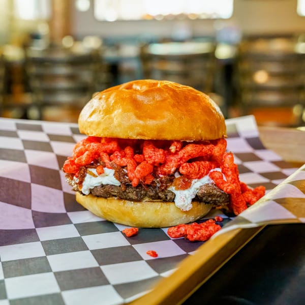 Lindy's on 4th burger with a beef patty, white sauce, caramelized onions, and red crunchy toppings.