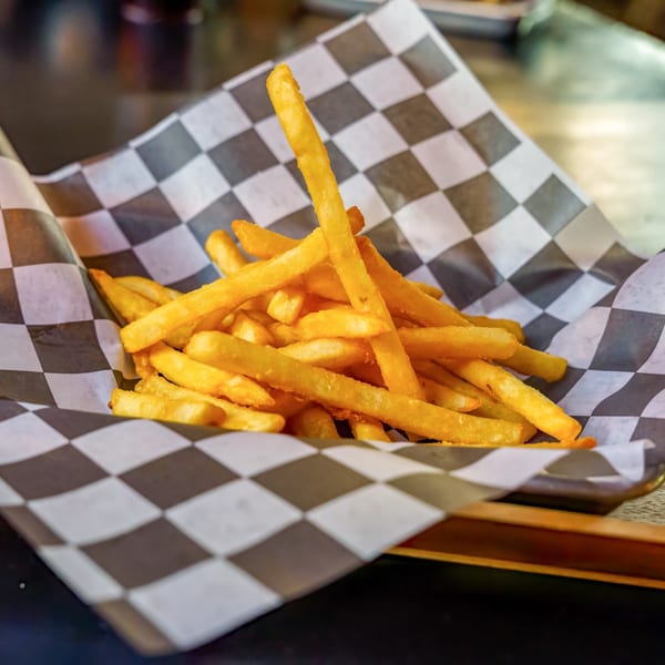 Golden french fries in a black and white checkered paper-lined basket at Lindy's on 4th.