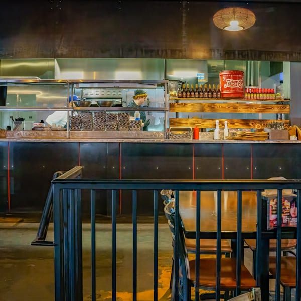 A Lindy's on 4th kitchen with a chef, stainless steel equipment, and a vintage Pepsi-Cola sign.