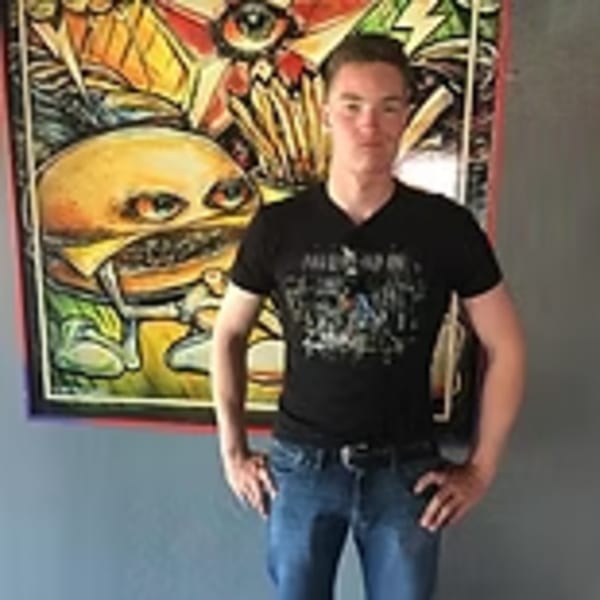 Man standing in front of a colorful, cartoonish burger painting at Lindy's on 4th.