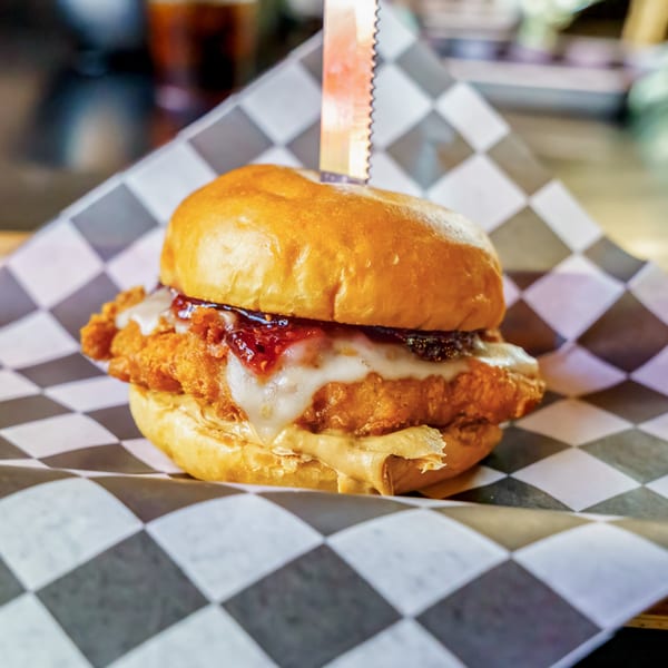Lindy's on 4th burger with fried chicken, melted cheese, jam, and peanut butter on a bun.