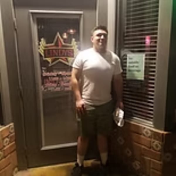 Man standing outside Lindy's on 4th restaurant entrance with a star-shaped neon sign.