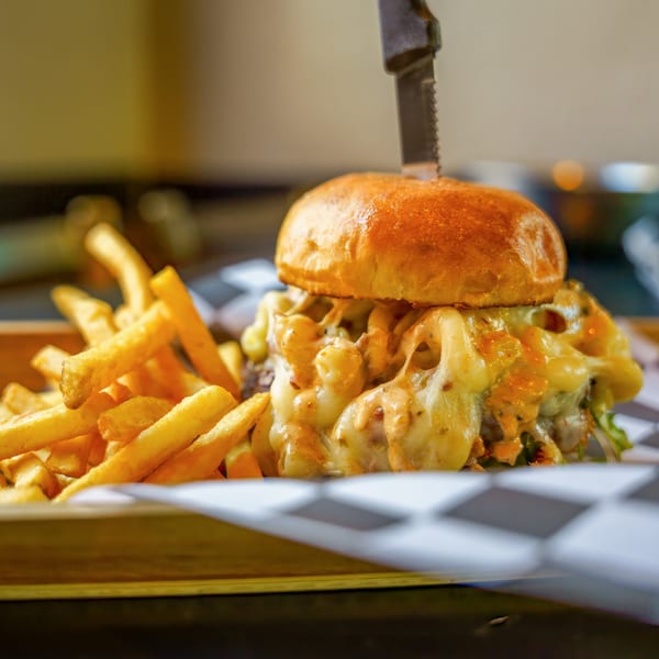 A Lindy's on 4th burger with melted cheese and a knife, served with golden fries.