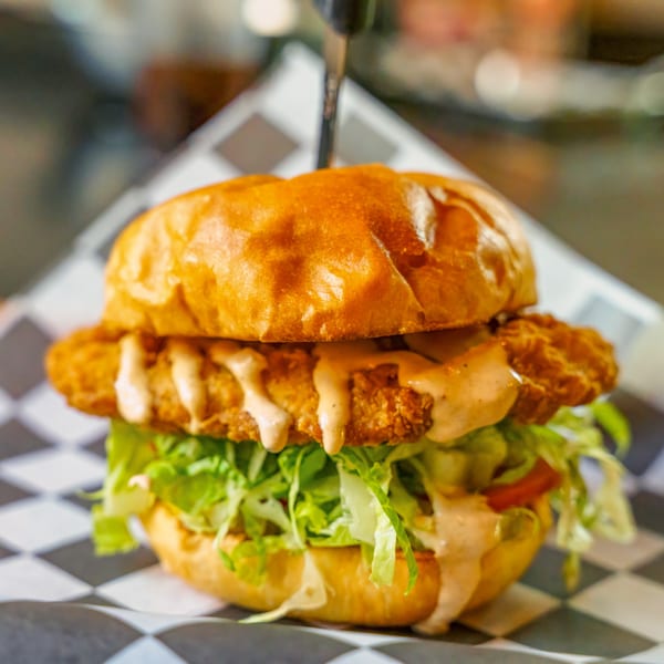 Lindy's on 4th crispy chicken sandwich with lettuce, tomato, and special sauce on a bun.